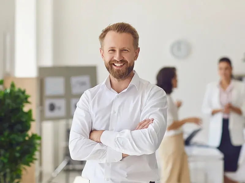 Smiling company employee standing standing at the office door.